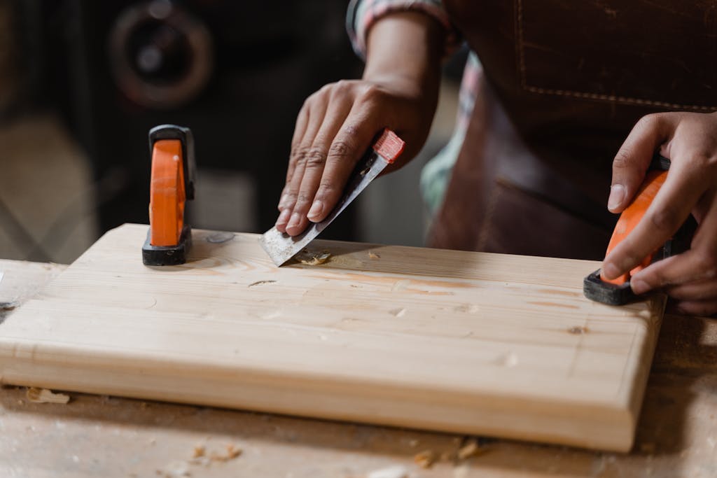 Hands crafting a wooden plank with clamps and tools. A focus on precision woodworking.
