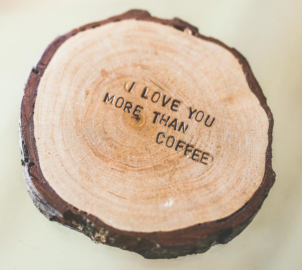 Rustic wooden coaster with the quote 'I love you more than coffee' engraved on it.